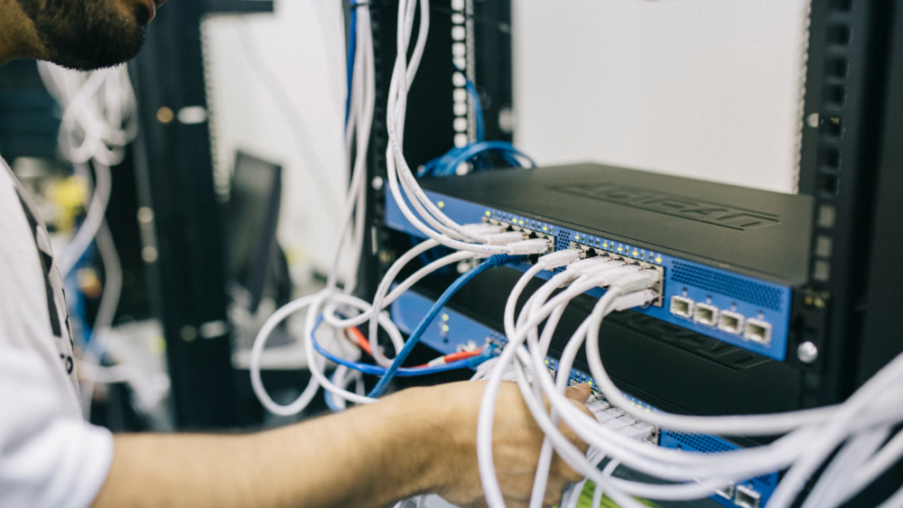 IT technician managing network cables and configuring a server rack for data center operations.